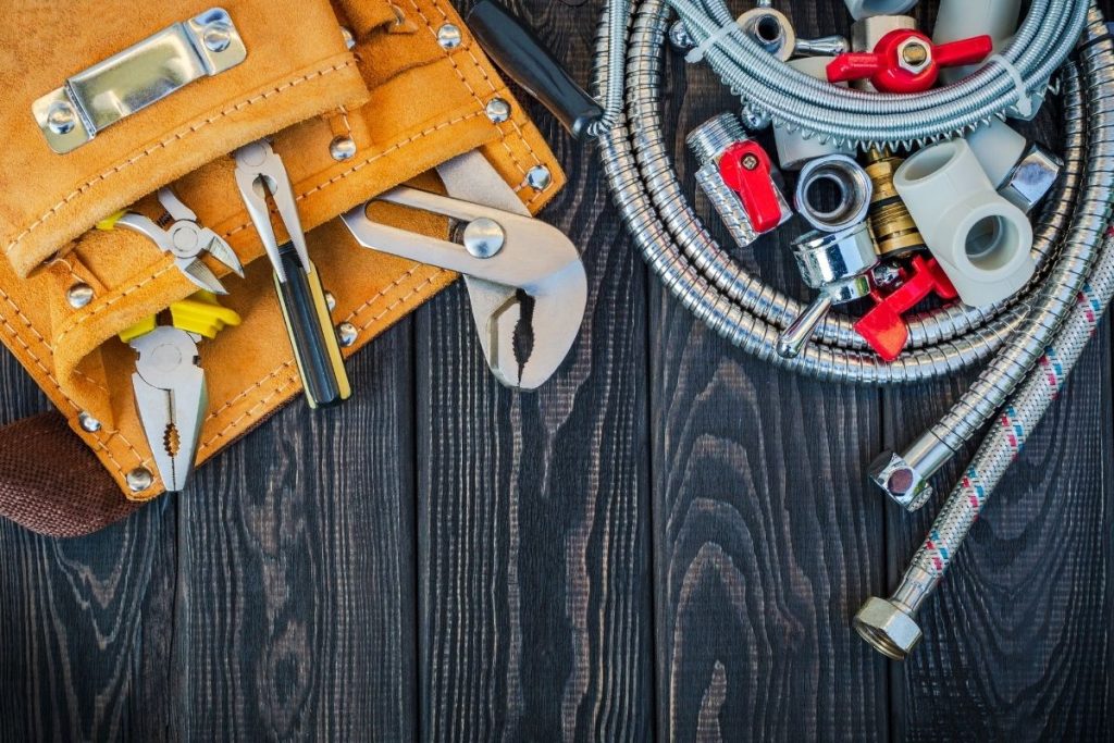 An assortment of hand tools displayed on a wooden table, featuring pliers, hammers, and screwdrivers, ready for use.